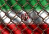 Iran flag behind a rusty chain-link fence