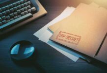 Top secret file folder on desk with magnifying glass and typewriter