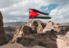 Palestinian flag waving over rocky desert cliffs