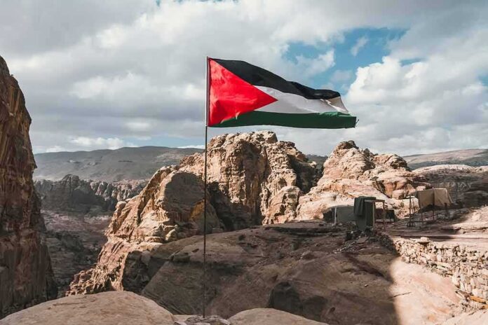 shutterstock_1260266692 Palestinian flag waving over rocky desert cliffs