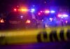 Police cars with flashing lights behind yellow caution tape at night
