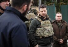 man in tactical vest standing with group outdoors