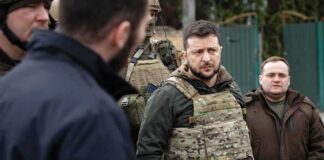 man in tactical vest standing with group outdoors
