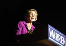 Woman in purple blazer speaking at a podium
