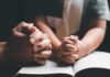 Bible Muzzle EXPOSED – Costly Apology Adult and child hands clasped in prayer over an open book