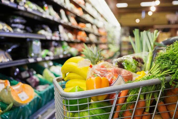 shopping cart filled with fresh produce in a grocery store aisle