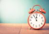 red retro alarm clock on wooden table