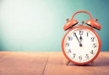 red retro alarm clock on wooden table