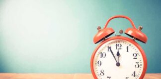red retro alarm clock on wooden table