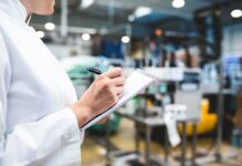 Inspector writing on clipboard in factory